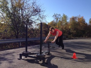 Personal training client pushing sled outdoors
