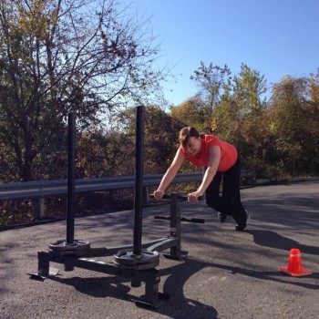Personal training client pushing sled outdoors