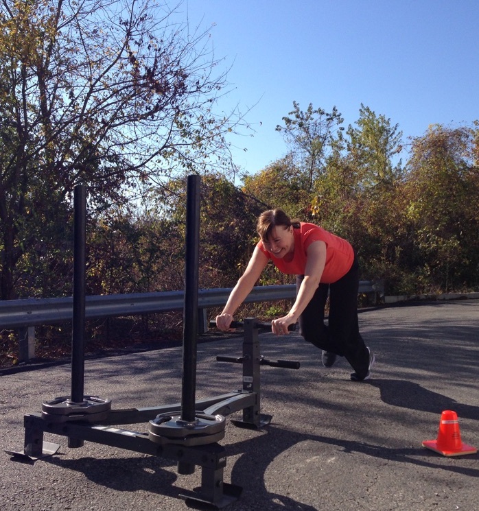 Personal training client pushing sled outside